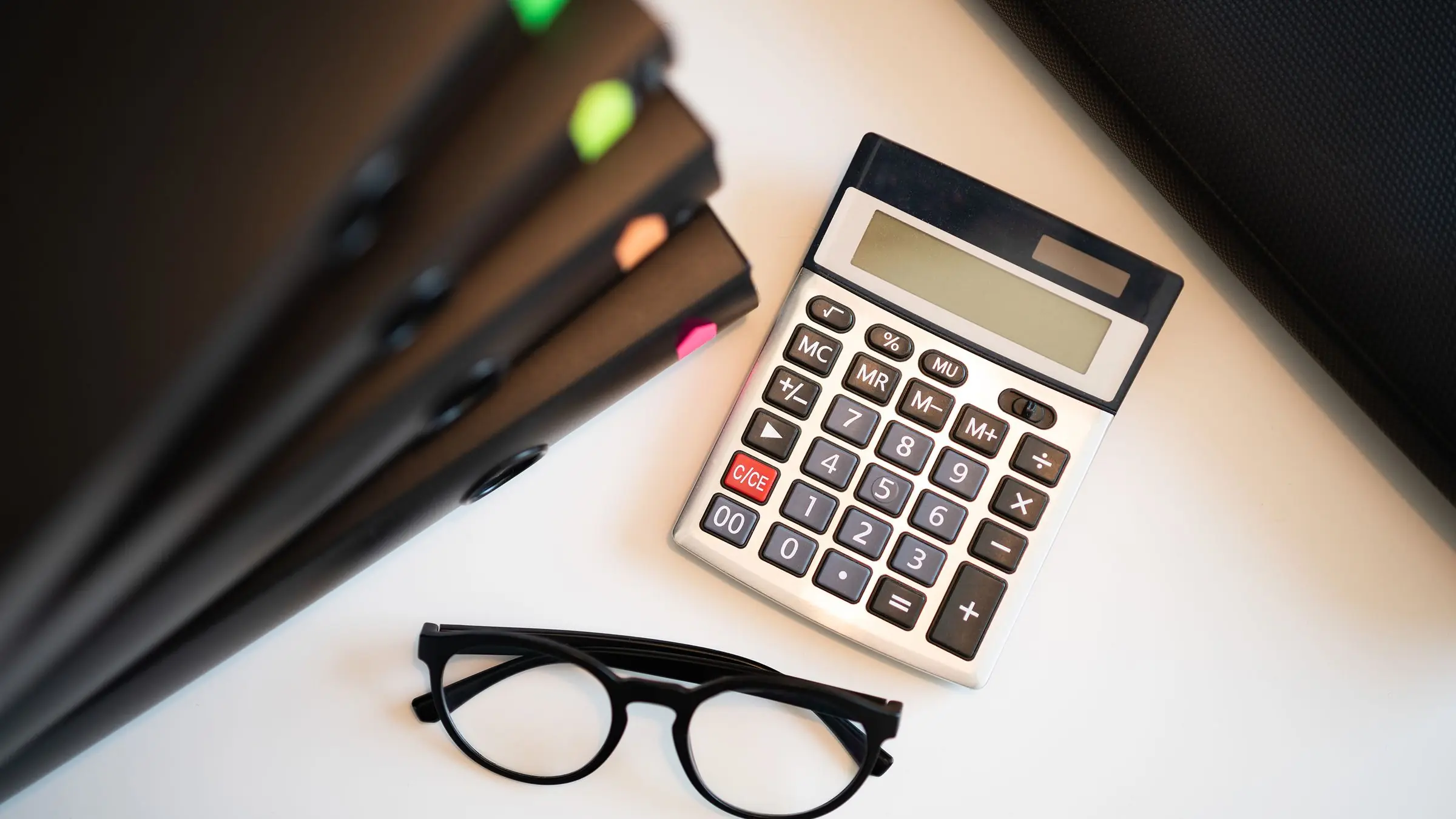 Calculadora, gafas y cuadernos de contabilidad sobre una mesa de trabajo