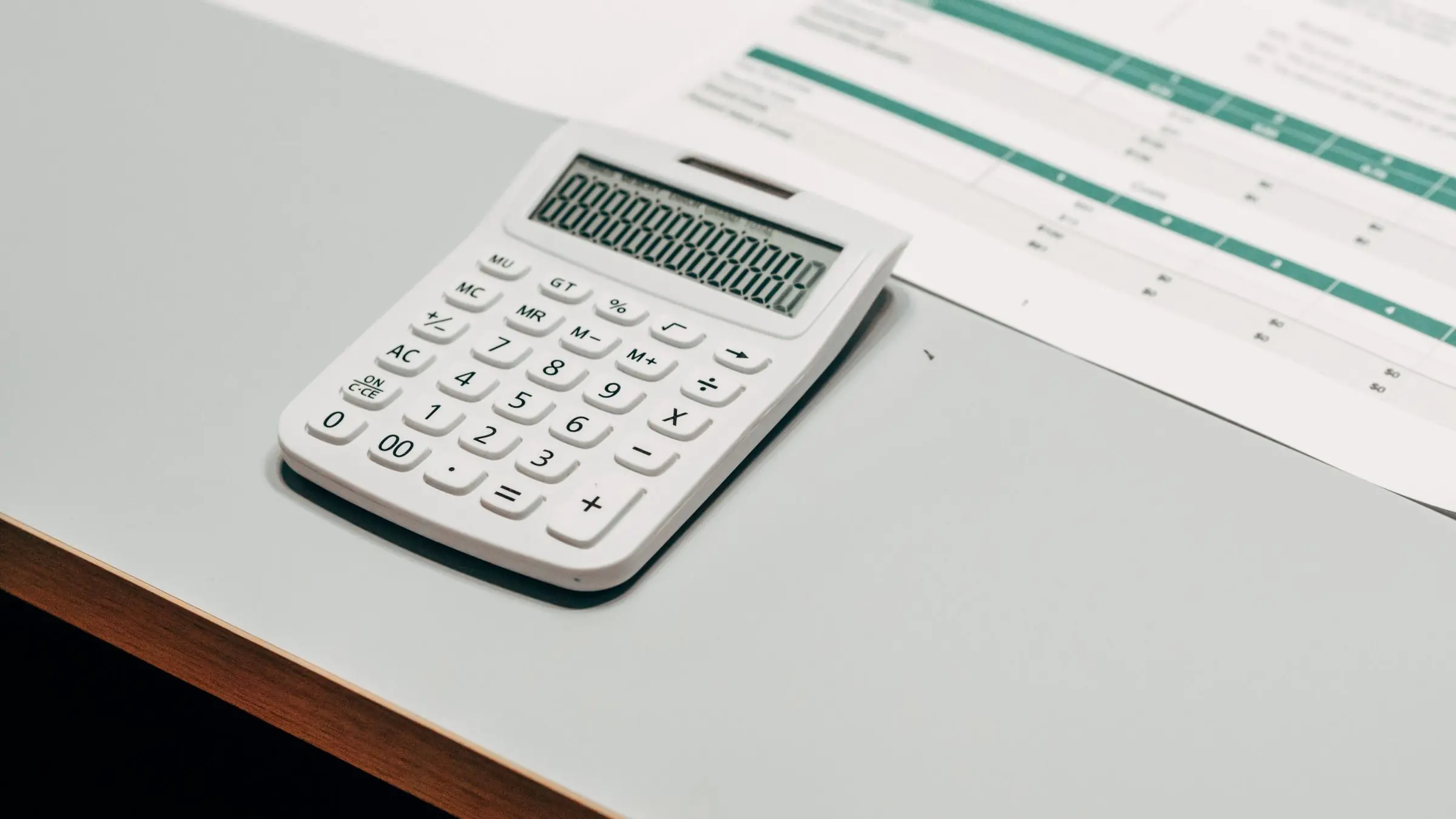 Calculadora sobre una hoja de cálculo impresa en la mesa de una asesoría