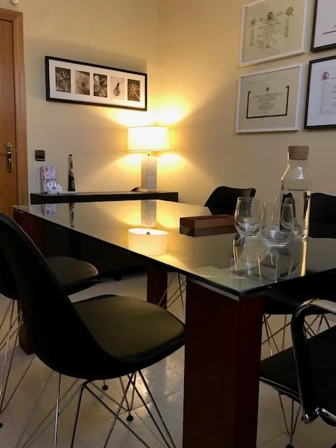 Sala de reuniones del despacho de Gesnova Asesores, con mesa de cristal, sillas negras y varios títulos enmarcados en la pared